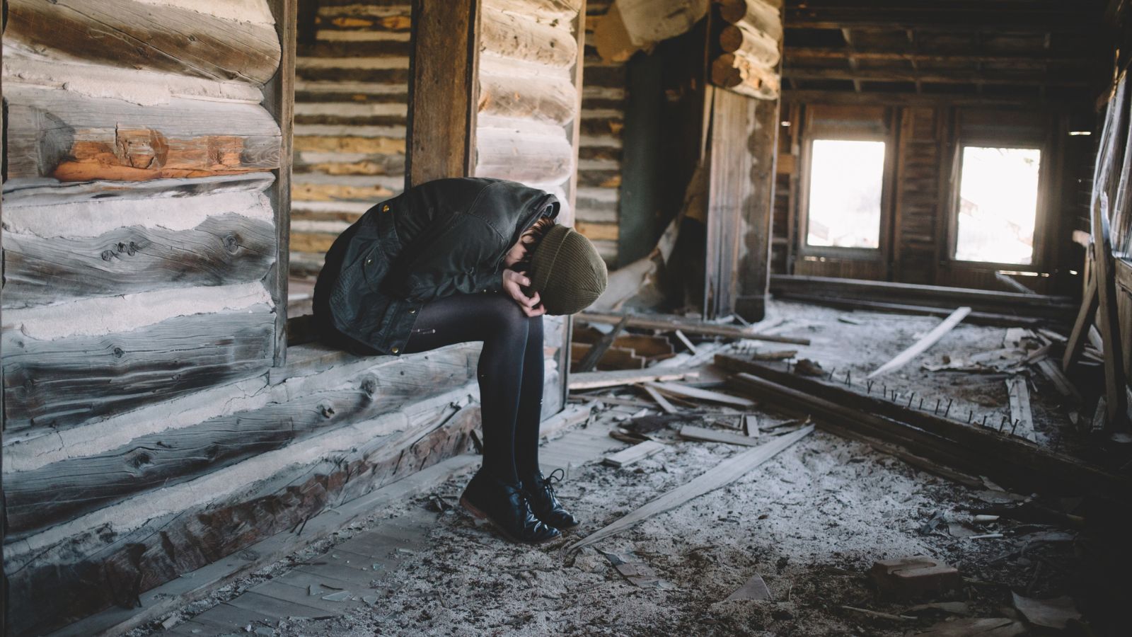 a woman bent over in grief in an abadoned log