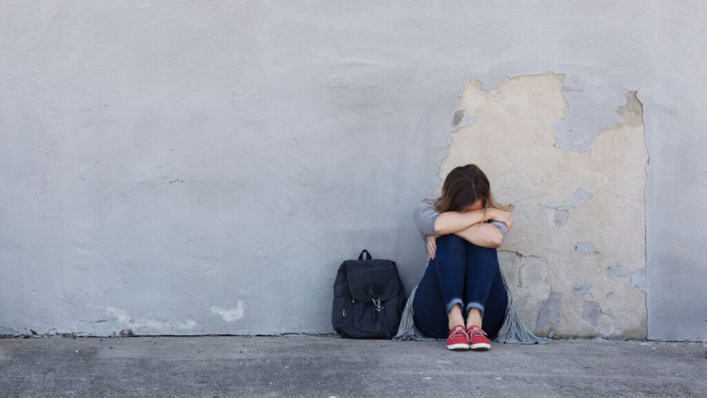 girl with a book bag hiding her face