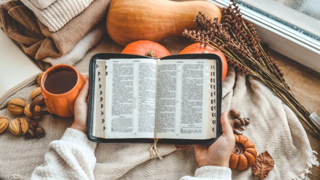 open bible woman hands in autumn interior