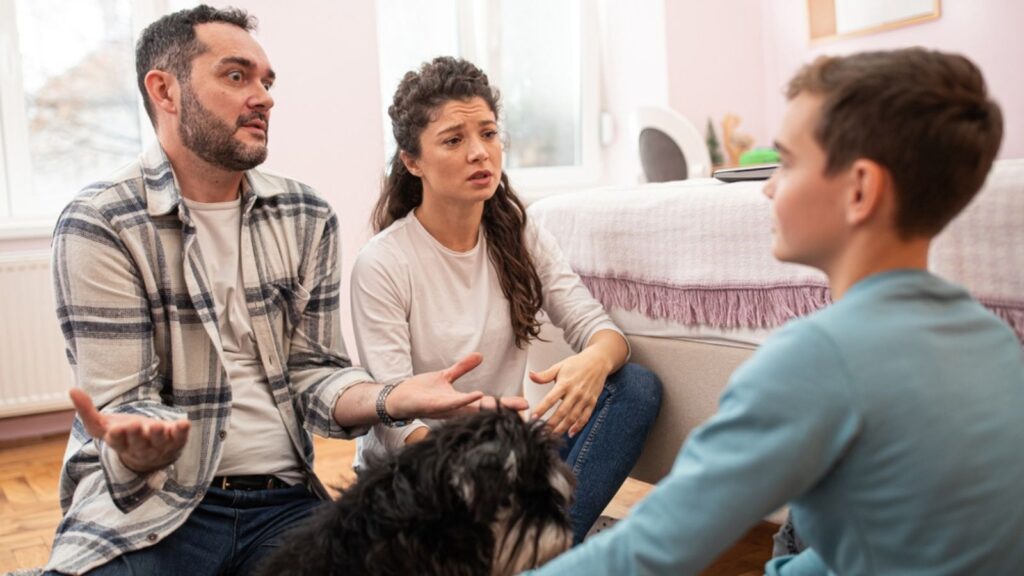 Angry parents having serious talk with boy in his room