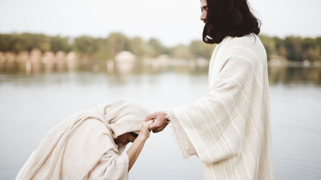 woman grabbing the hand of Jesus Christ for healing and help