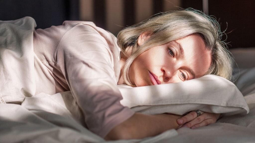 Stressed woman lying on bed at home and crying. Unhappy woman suffering from nervous tension, emotional disorders, psychological problems,