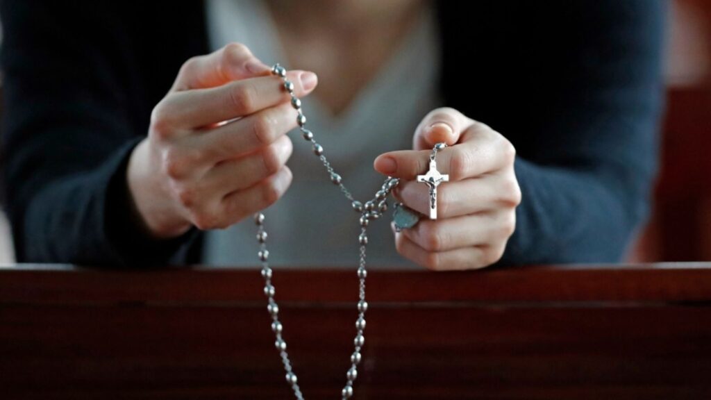 hands of woman praying with rosary ,crucifix