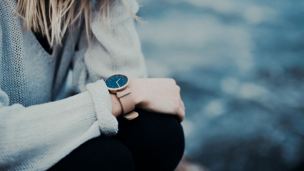woman sitted on a stone wall cheking her watch,god`s timing