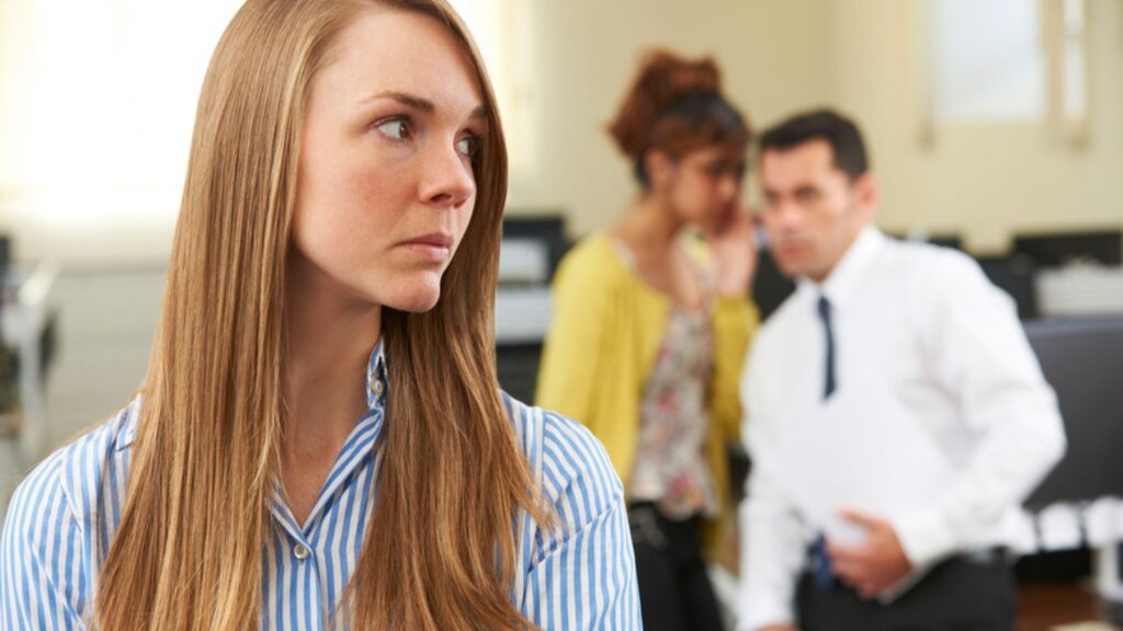 Businesswoman being gossiped about by colleagues in the office