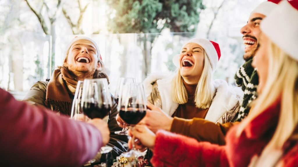 Happy family wearing santa claus hat having Christmas dinner party- Cheerful group of friends sitting at restaurant dining table celebrate xmas holiday