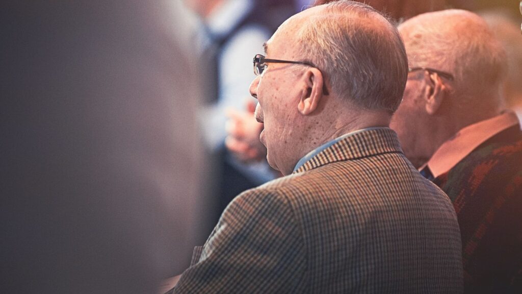 elderly men sitting in church pews at a worship service
