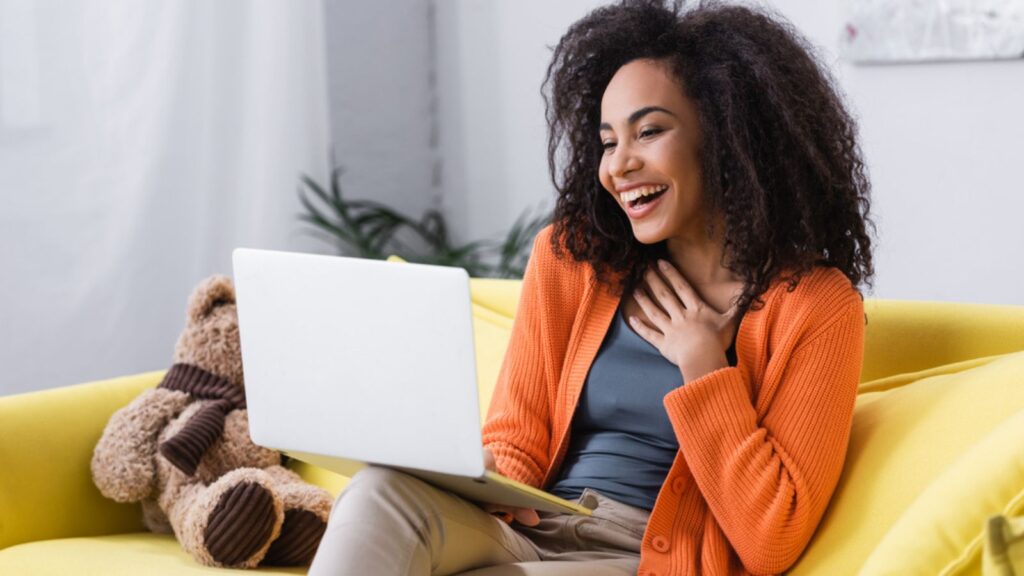 joyful african american freelancer using laptop at home
